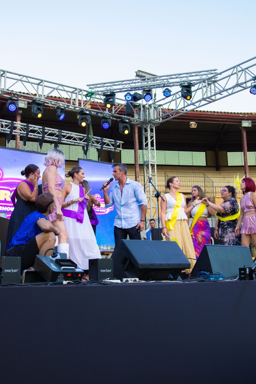 Concursantes del equipo morado y del equipo amarillo sobre el escenario con Alonso Caparrós y su micrófono en Furor The Show