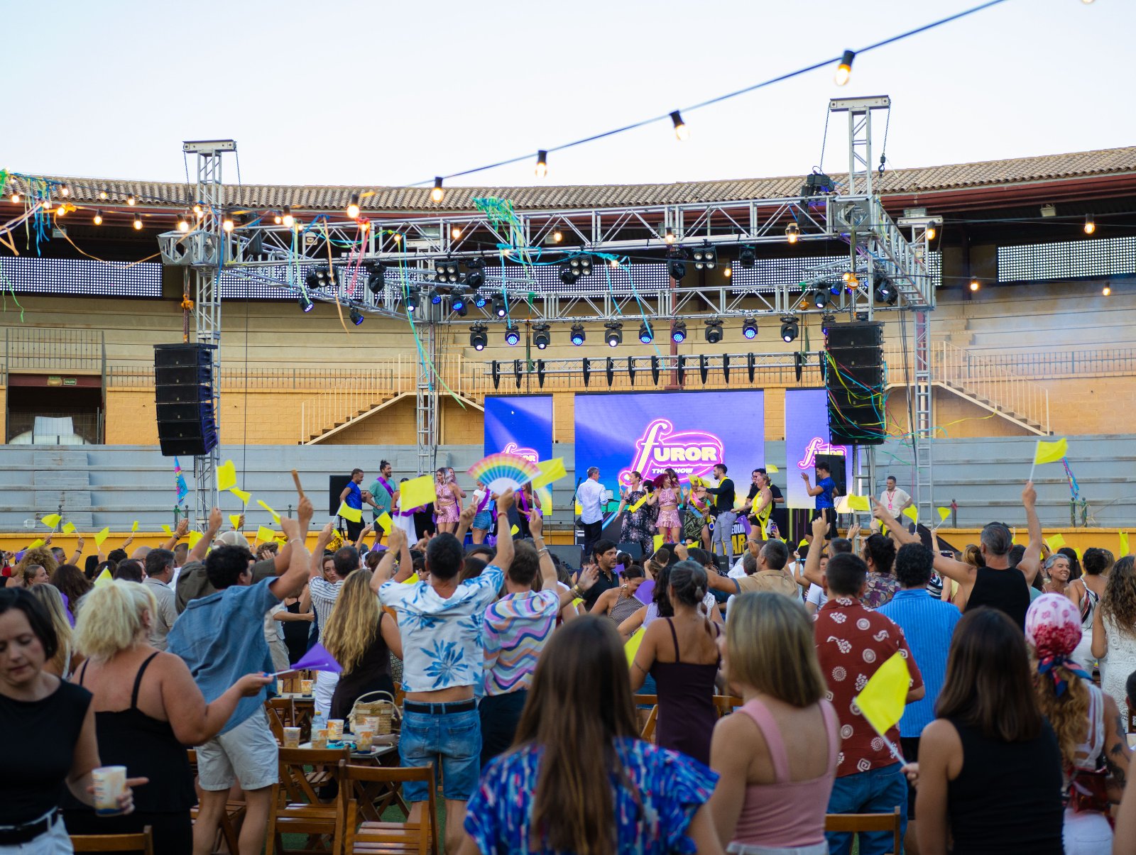 Público del equipo amarillo animando con banderines frente a la pantalla de Furor The Show en Plaza Paraíso Torremolinos