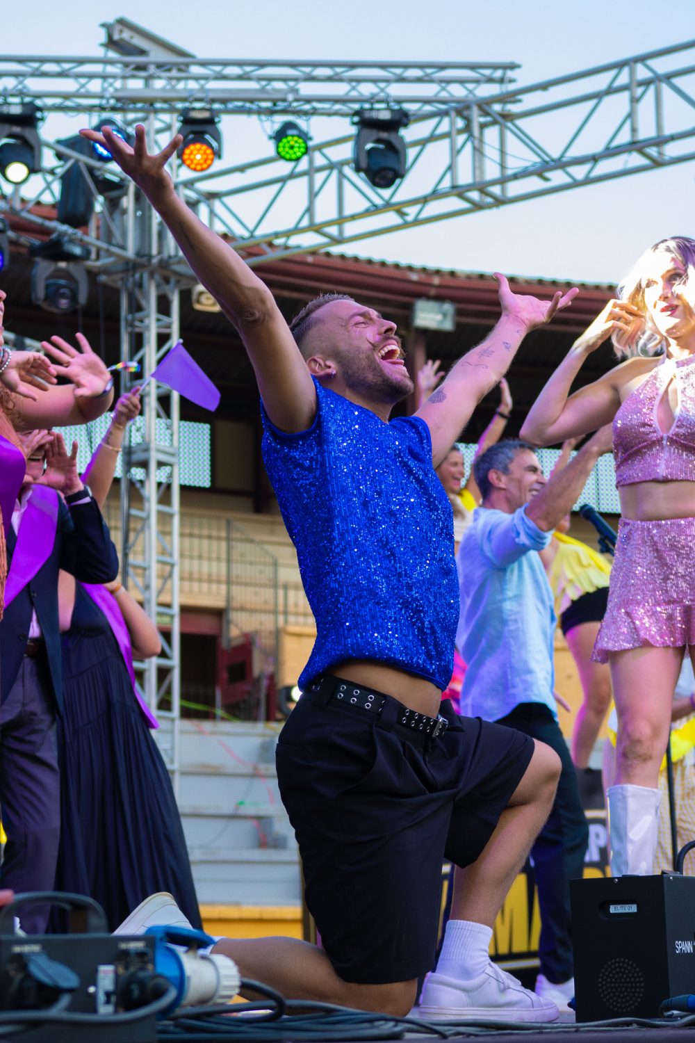 Bailarín del elenco de Furor The Show cantando de rodillas en el escenario junto a las azafatas del programa
