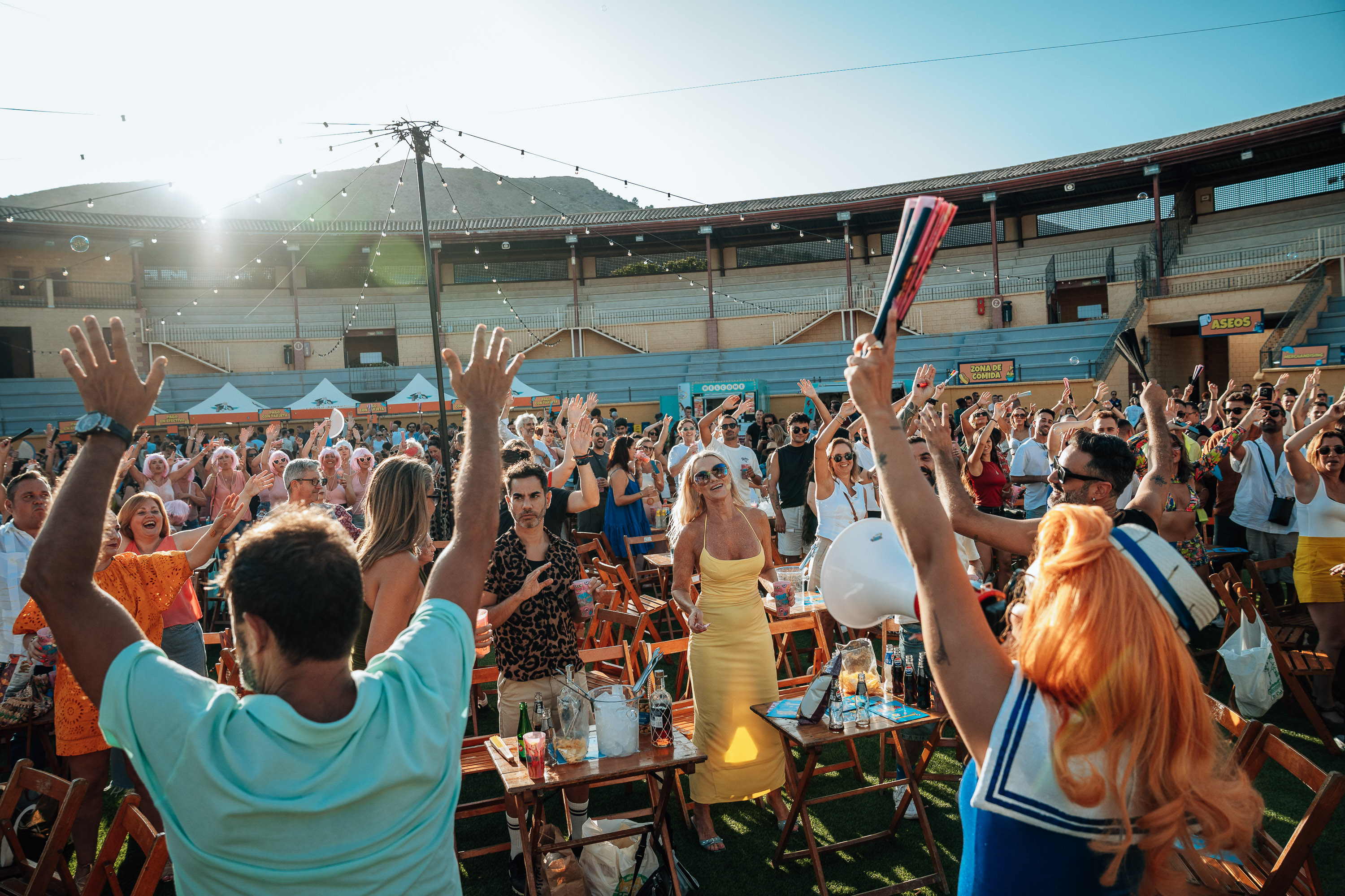 Público con los brazos en alto y abanicos en una fiesta al aire libre en la Plaza de Toros de Torremolinos